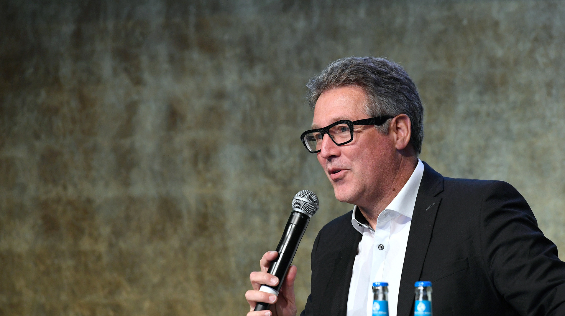 Johannes Kreißig als Referent auf dem Podium Johannes Kreißig als Referent auf dem Podium mit Mikrofon beim DGNB Tag der Nachhaltigkeit 2022